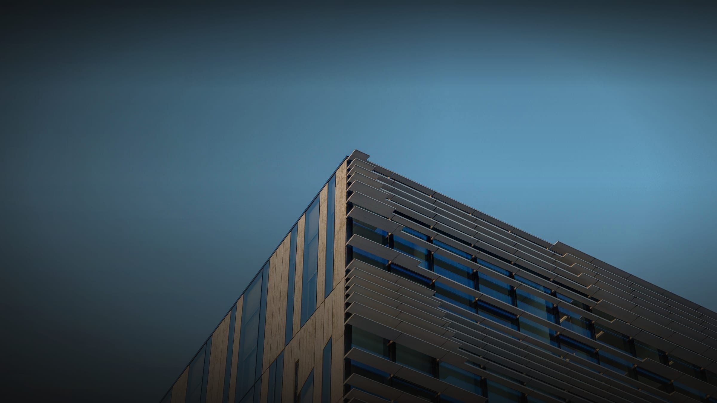 Low angle view of a modern building facade combining two cladding systems against a clear sky